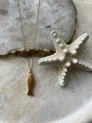 Starfish and gold necklace on a textured surface
